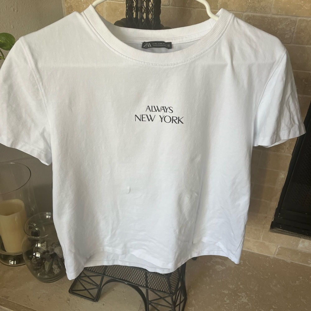 Zara White Tee that reads “Always New York”.  Sits at or above waist.
